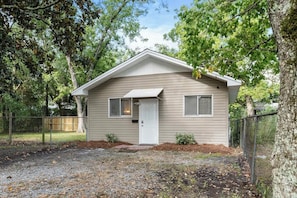 A single-story house with a front door, two windows, and a small porch.