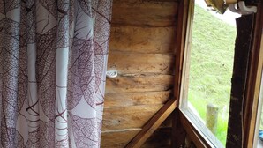A wooden cabin interior with a window overlooking a grassy area. - Glamping Rustiko Salento  (Salento)