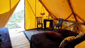A cozy tent interior with a wooden floor, a table, chairs, and a sofa. - Glamping Rustiko Salento  (Salento)