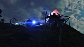 Een tentvormige constructie op een heuvel, met een heldere lucht.