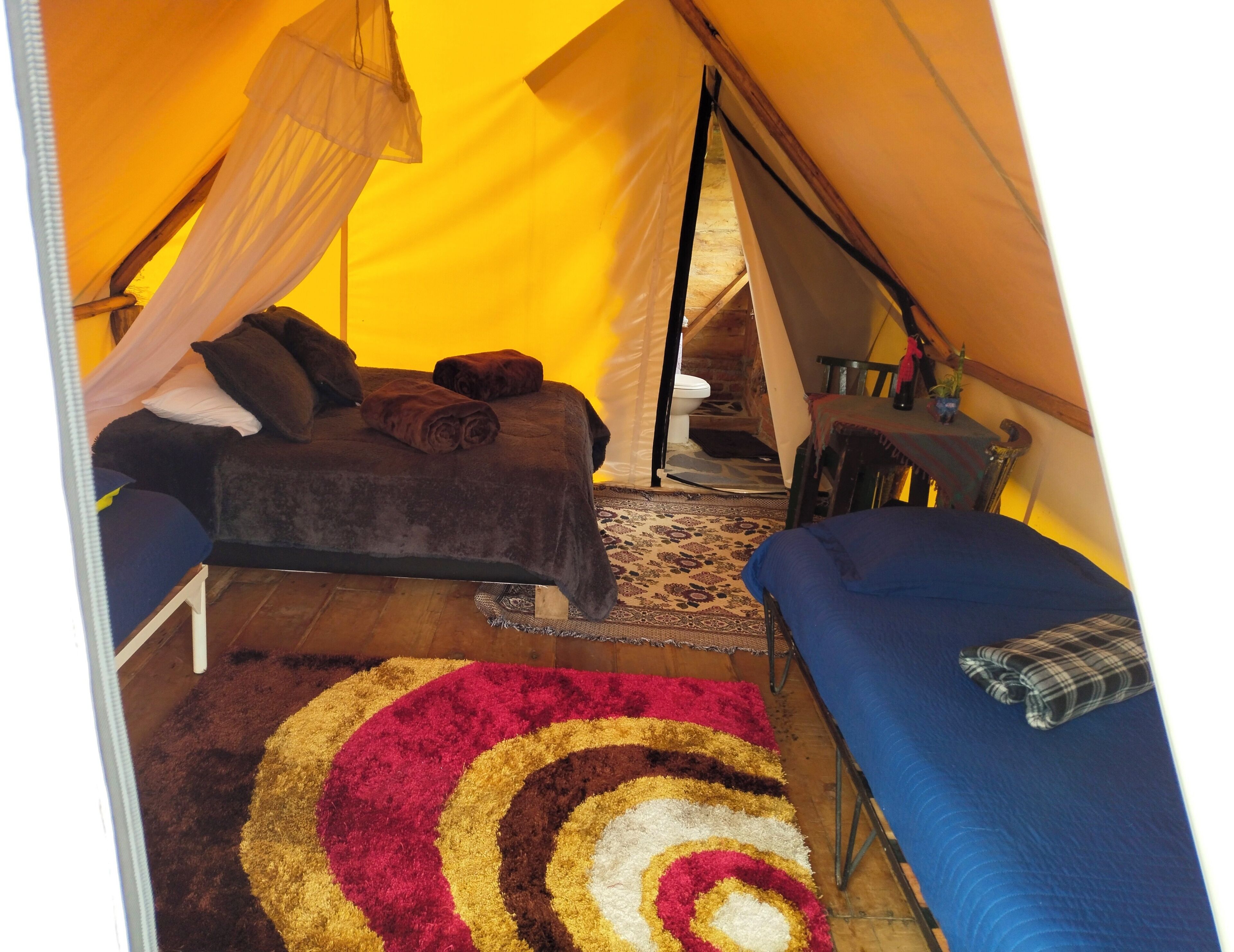 A tent with a bed, a small table, and a chair.