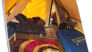 A tent with a bed, a small table, and a chair.