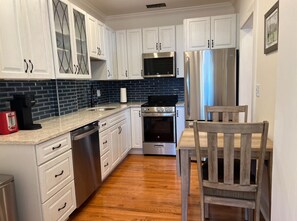 A kitchen with white cabinets, a stainless steel refrigerator, a microwave, a stove, and a dishwasher. - Charming apartment with pool, free parking, walk to everything downtown. (St. Augustine)