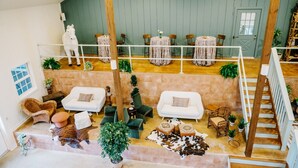 Un vaste espace de vie de style loft, doté d’un plafond haut, d’un escalier en bois et d’un coin salon avec des canapés et des fauteuils.