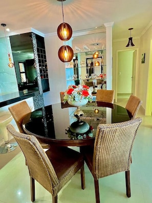 A dining area with a round glass table, wicker chairs, and a decorative centerpiece.