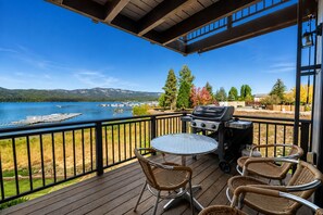 A deck with a grill, chairs, and a table overlooking a lake with boats and trees. - Shores Lakefront Condo - Lakefront Condo, Walk to Village, Dock, Pool (Big Bear Lake)