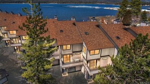 Un moderno edificio residencial de varios pisos con vistas a un lago y montañas.