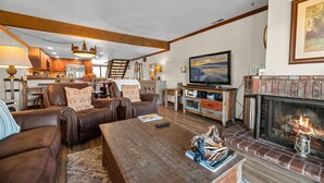 Una sala de estar acogedora con chimenea, sofás de cuero, una mesa de centro y un televisor.