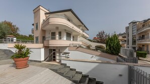 Un immeuble résidentiel à plusieurs étages, doté d’une façade incurvée, de balcons et d’un escalier menant à l’entrée.