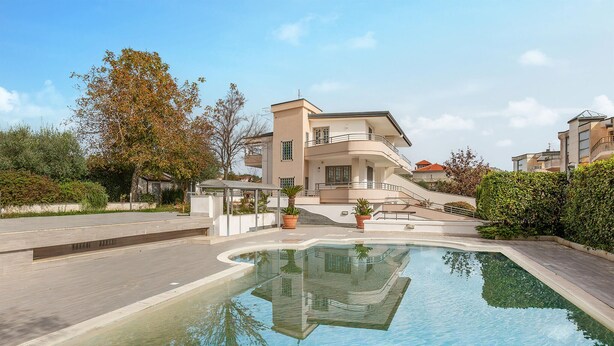 Un immeuble résidentiel moderne doté d’une piscine, d’un espace extérieur couvert et d’un jardin aménagé.