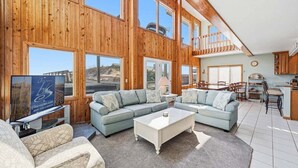 A spacious living area with a large sectional sofa, a coffee table, and a television. - Fancy Free | Oceanfront | Hot Tub (Nags Head)