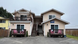 A two-story building with a central staircase, a parking lot, and a wooden fence.