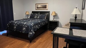 A bedroom with a bed, two bedside tables, a desk, and a chair.