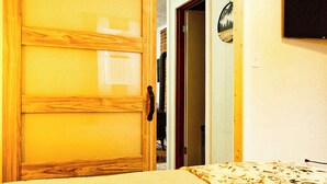 A room with a sliding wooden door, a bed with a patterned bedspread, and a wall-mounted TV. - Winter Bliss at Powderhorn Mountain (Bessemer)