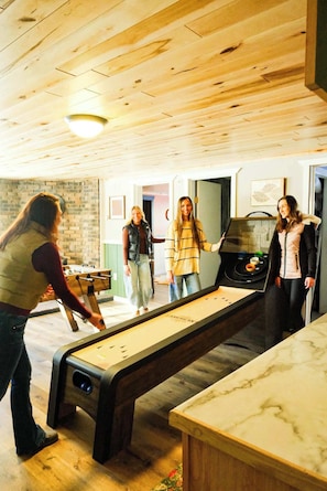 A room with a foosball table, a billiards table, and a marble-top table.