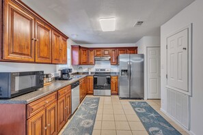 Una cocina con armarios de madera, electrodomésticos de acero inoxidable y un tapete estampado.