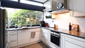 A modern kitchen with white cabinets, a built-in oven, a coffee maker, and a clock on the wall. - (WOH15) Holiday home "Kapitänsresidenz" - Holiday home "Kapitänsresidenz" up to 8 persons (Timmendorfer Strand)