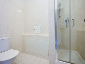 A bathroom with a toilet, a shower enclosure, and a wall-mounted control panel.