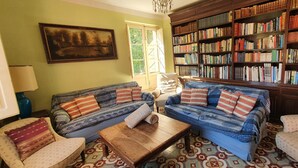 Un salon chaleureux avec deux canapés, une table basse et une bibliothèque remplie de livres.