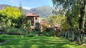 Une maison avec un toit rouge et un jardin à l’avant.