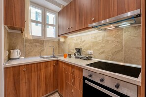 A kitchen with wooden cabinets, a stainless steel range hood, a coffee maker, and a kettle.