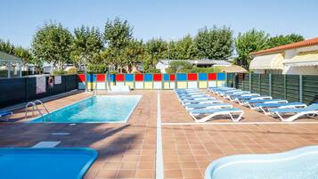 A swimming pool with lounge chairs, a tiled deck, and a colorful fence.