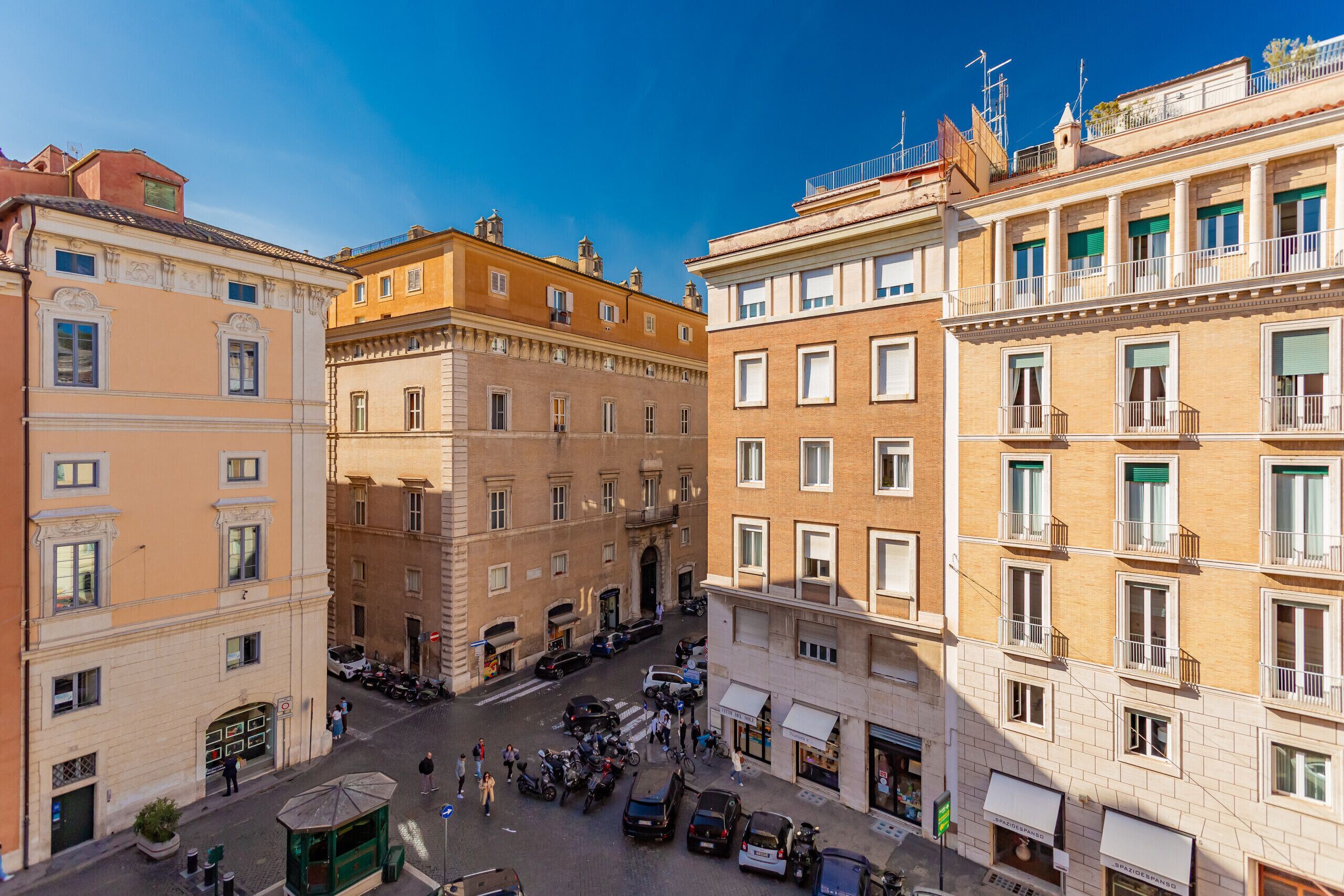 A street view of a European city with historic buildings, a central square, and a tram stop.