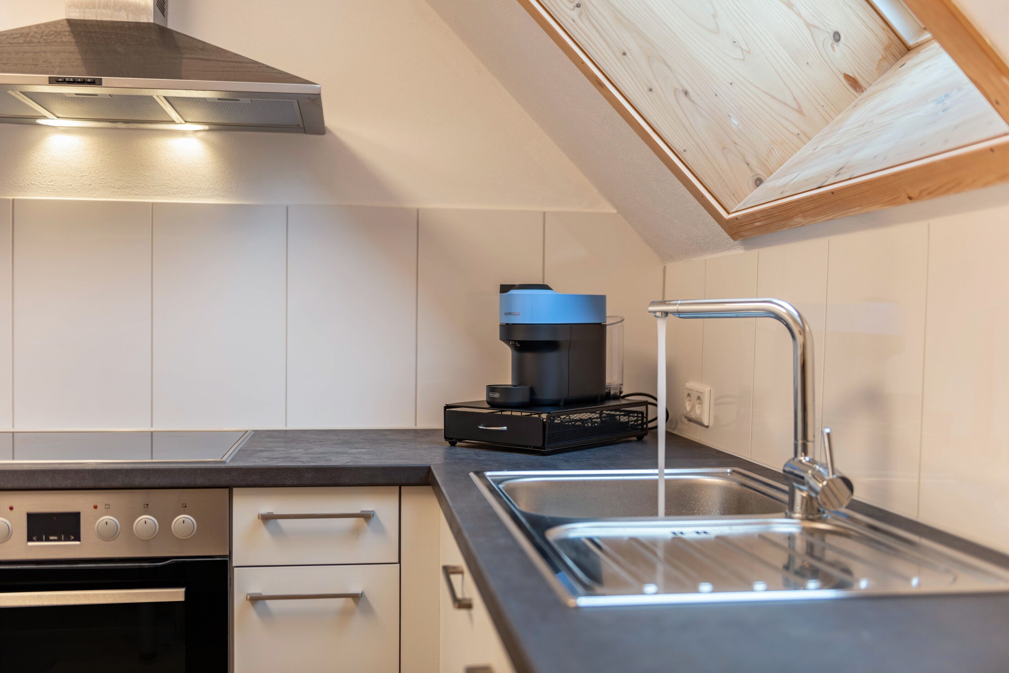 Una cocina con horno empotrado, cafetera y lavabo.