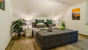 A bedroom with a bed, bedside tables, a lamp, a potted plant, and a painting on the wall. - Apartment 'Bergblick' with Shared Terrace, Sauna, Whirlpool & Pool (Stockach)