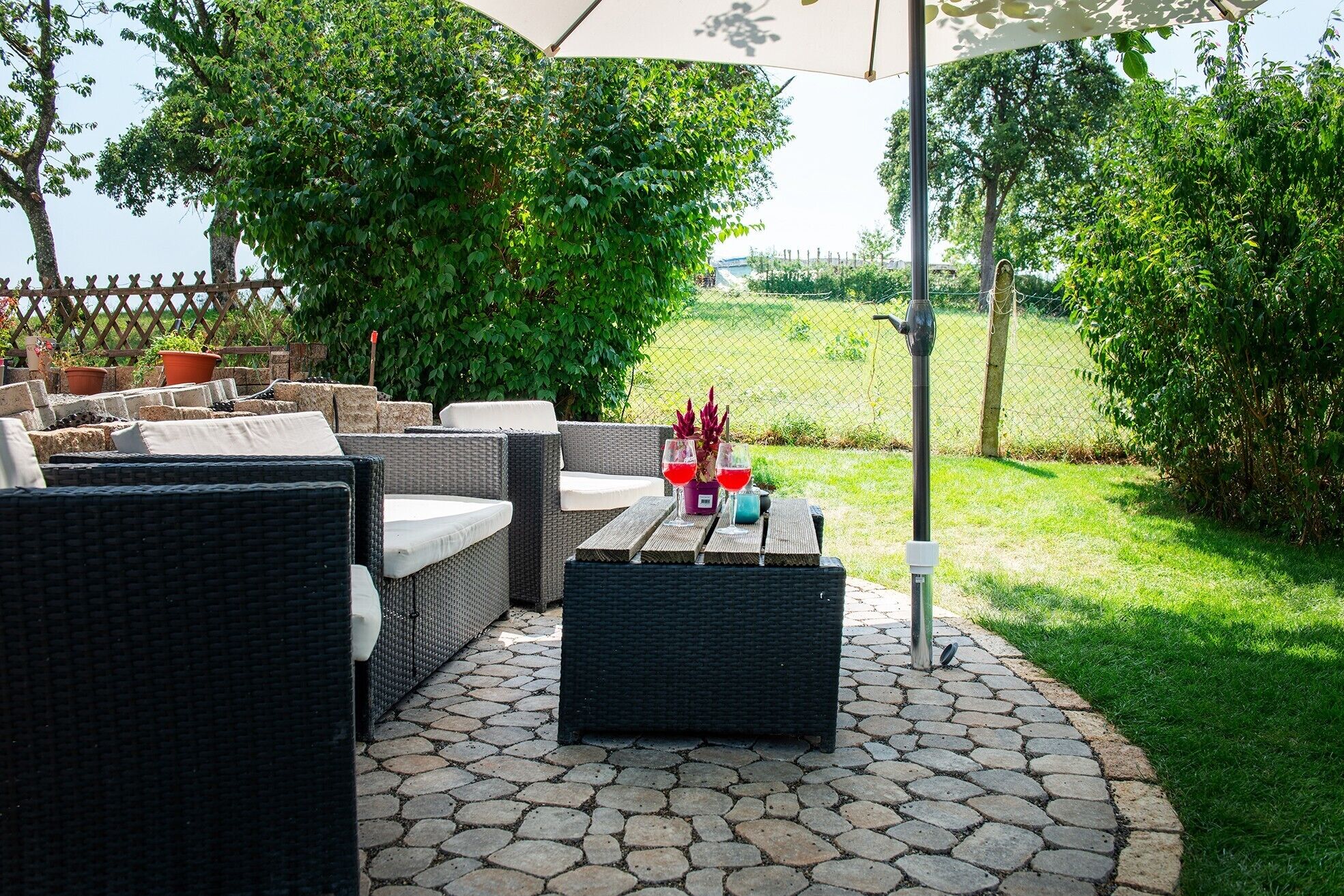 Un patio exterior con muebles de mimbre, una mesa y una planta en maceta.