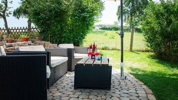 Un patio exterior con muebles de mimbre, una mesa y una planta en maceta.