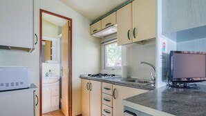 A compact kitchen with a microwave, stove, sink, and a flat-screen TV. - Bungalow 'A4' with Private Pool, Private Terrace and Wi-Fi (Pontevedra)