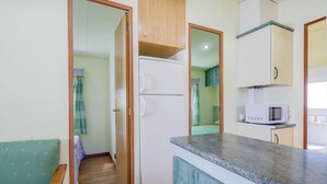 A compact kitchen with a refrigerator, microwave, and a small countertop. - Bungalow 'A4' with Private Pool, Private Terrace and Wi-Fi (Pontevedra)
