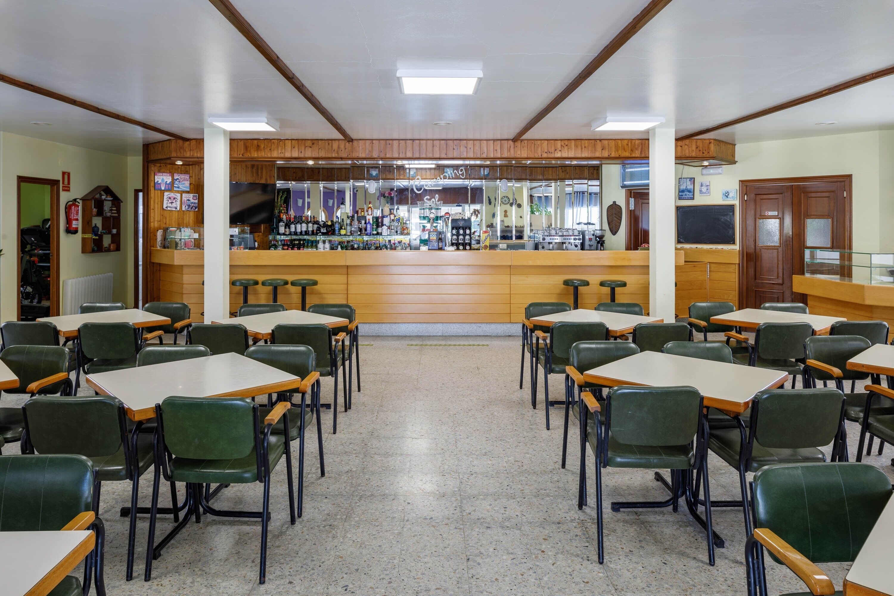 A restaurant with a bar area, multiple tables, and chairs.