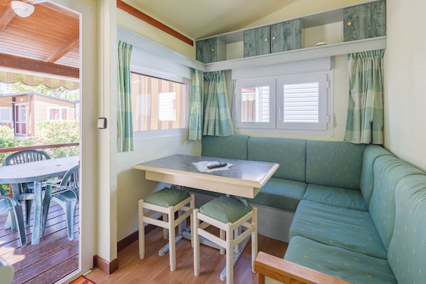 A cozy room with a table, two chairs, a bench, and a window with curtains.