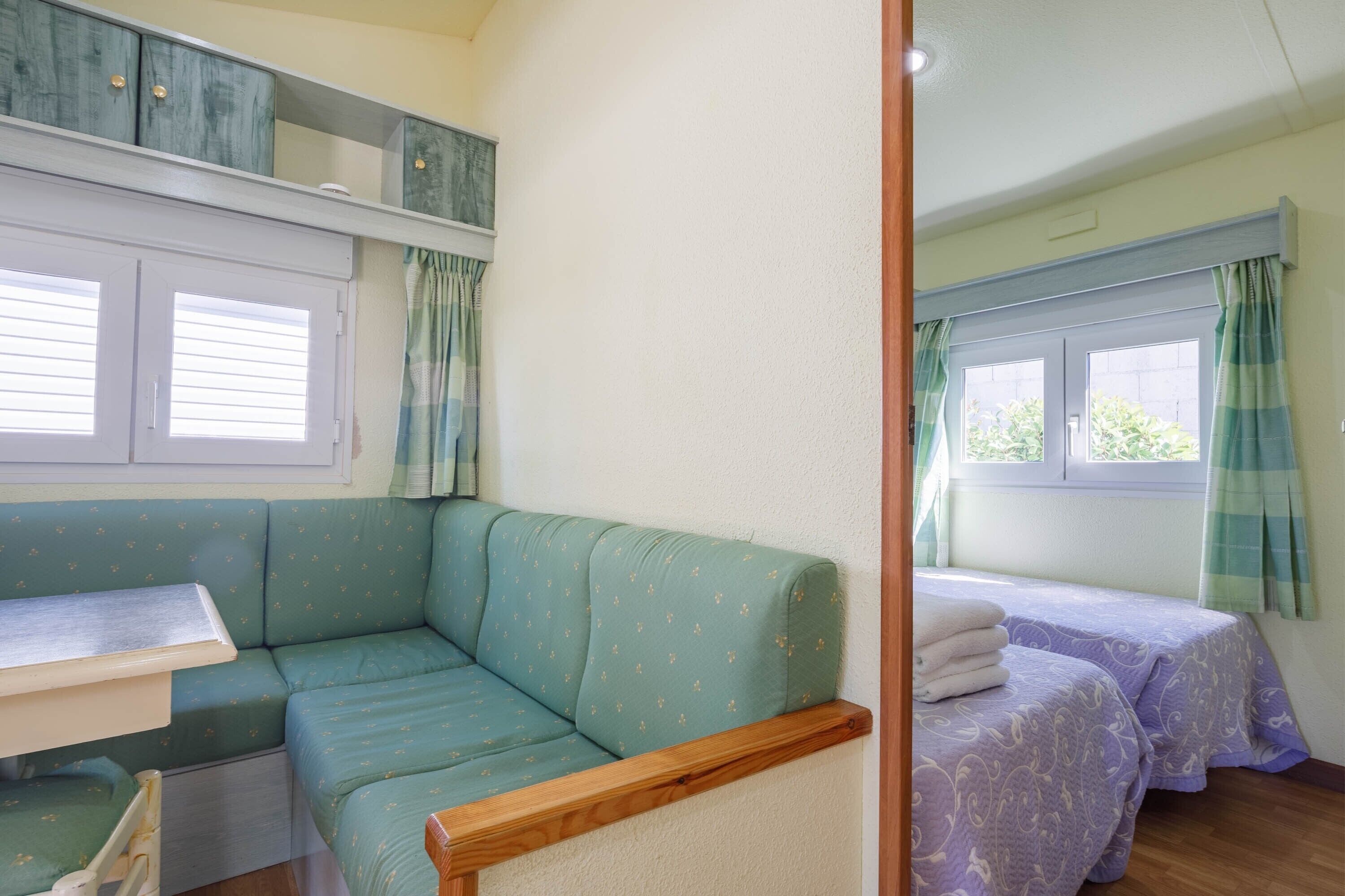 Ein gemütliches Zimmer mit einer Couch, einem Bett, einem kleinen Tisch und einem Fenster mit Vorhängen.
