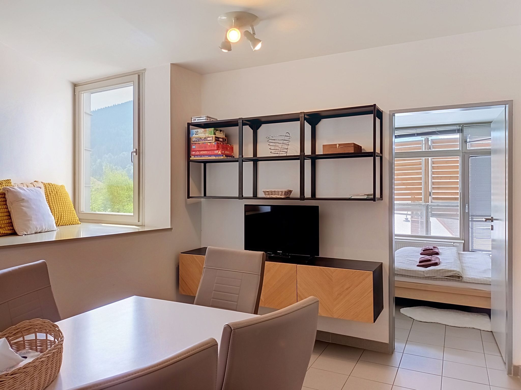 A modern living room with a dining area, a TV, and a bookshelf.