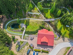 An aerial view of a park with a red-roofed building, winding paths, and a pond.