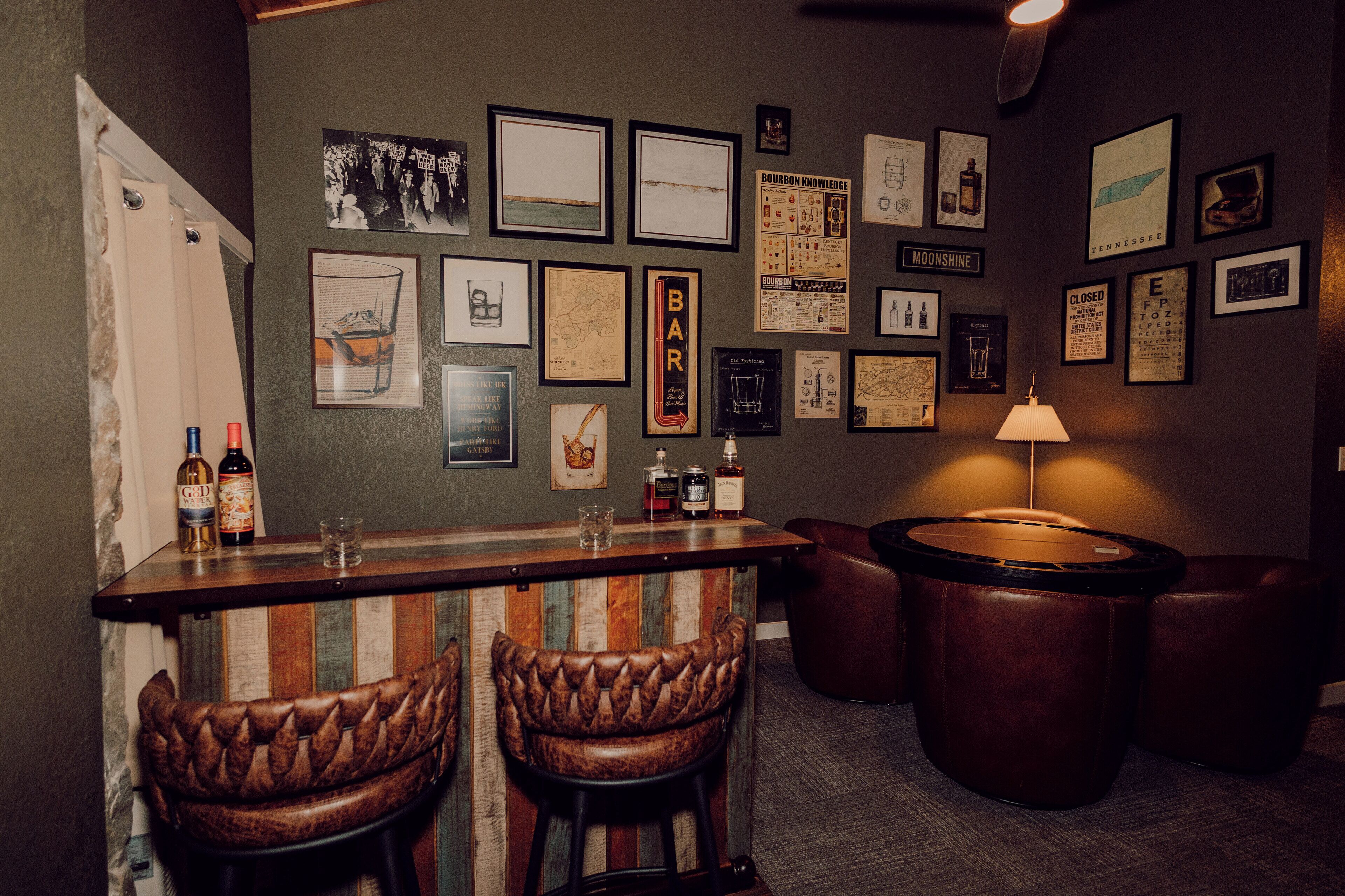 Una zona de bar con taburetes, una barra y varias fotografías enmarcadas en la pared.