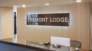 A reception desk with a sign reading "TREMONT LODGE" and a laptop on the counter.