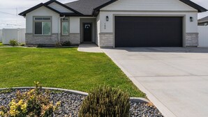 Una casa a un piano con garage, un prato curato e un giardino in primo piano con ghiaia e rocce.