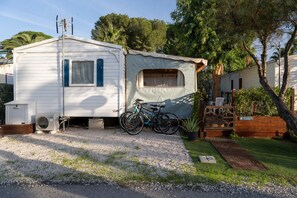 A mobile home with a covered porch, a bicycle, and a small garden area.