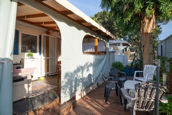 A covered patio with wooden flooring, outdoor furniture, and a view of a house.