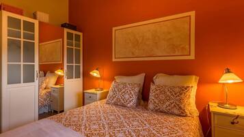 A bedroom with a bed, two bedside tables, a wardrobe, and a wall-mounted artwork.