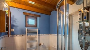 Une salle de bain équipée d’une douche, de toilettes, d’un lavabo et d’une fenêtre située au-dessus des toilettes.