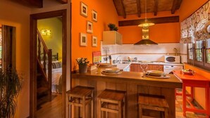 Une cuisine avec des tabourets de bar en bois, un four à micro-ondes et un luminaire suspendu.