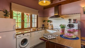 A compact kitchen with a washing machine, a microwave, and a coffee maker.