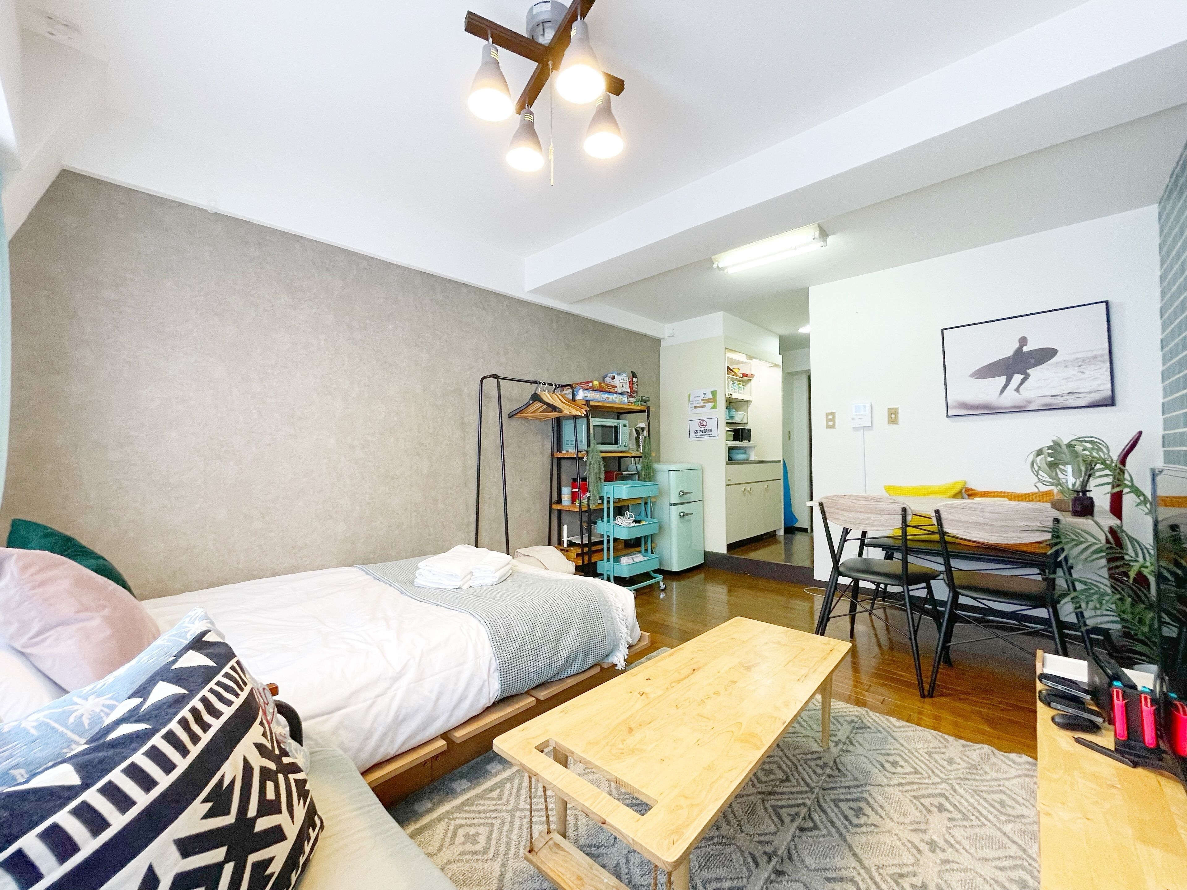 Una habitación moderna y bien iluminada con cama, una mesa de madera y una kitchenette.
