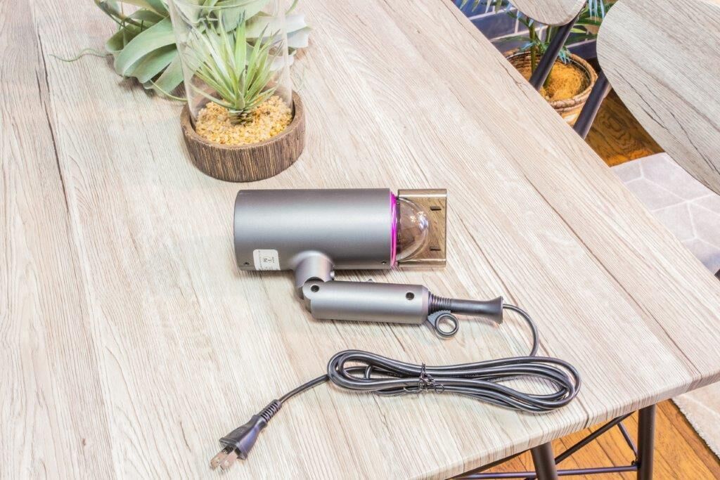 Een tafel met een cilindervormig apparaat, een opgerolde kabel en een kleine potplant.