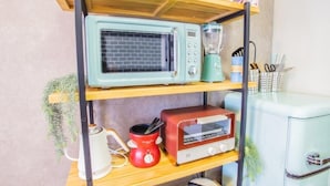 A kitchen shelf with a retro-style microwave, a red coffee maker, and a vintage toaster. - LVB Shibuyadogenzaka (Tokyo)